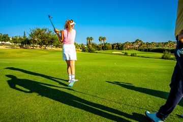 Golfer taking a shot on sunny golf course