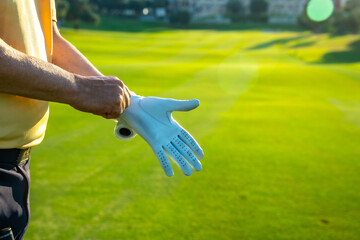 Golfer wearing golf glove on lush green course