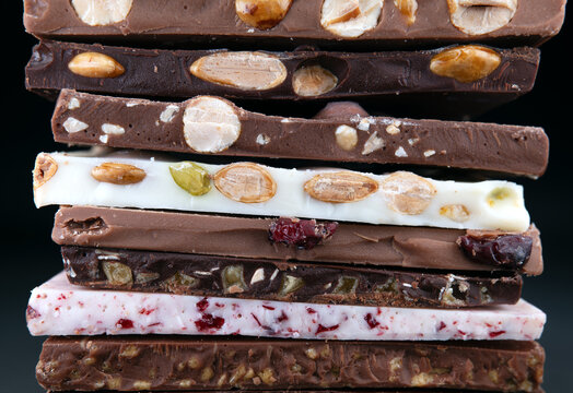 Handcrafted Belgian chocolate bars with nuts and dried fruits, stacked in a colorful and textured arrangement. - Powered by Adobe