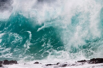 Blue wave crashing on coastal  rocks
