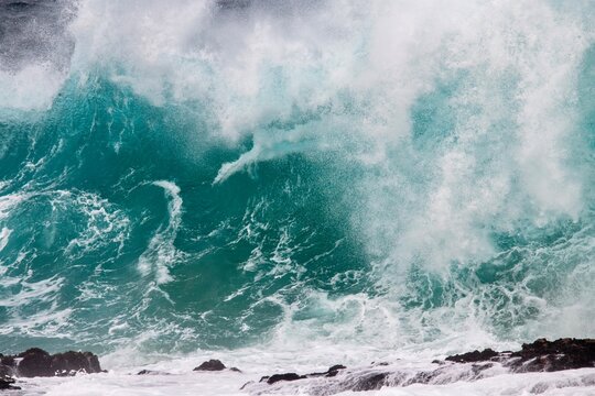 Blue wave crashing on coastal  rocks
