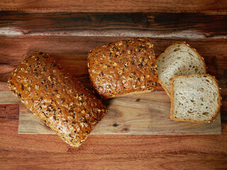 The photo shows two loaves of bread, one of which is sliced, on a wooden cutting board against a...