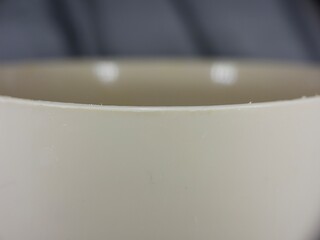 macro shot of the curved rim of a white ceramic bowl, showcasing its smooth, matte texture and soft...