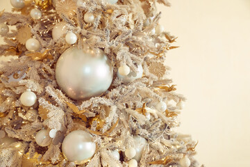 Obraz premium Festive Snowy Christmas Tree with Elegant Ornaments and Soft Bokeh Lights.gold and silver ornaments, Christmas tree decoration balls on beige background