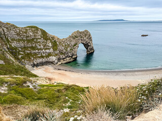 Early summer morning at Durdle Door in Dorset, England, UK. Durdle Door limestone arch on the Jurassic Coast in Dorset. Natural landmark. England. Pure clean clear water.