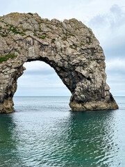 Early summer morning at Durdle Door in Dorset, England, UK. Durdle Door limestone arch on the Jurassic Coast in Dorset. Natural landmark. England. Pure clean clear water.