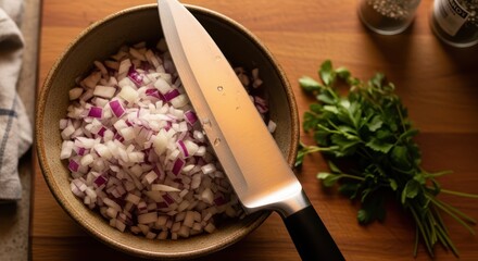 Diced red onions in bowl with knife on wooden cutting board