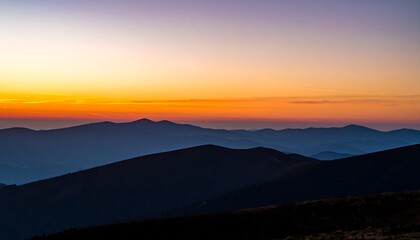 Fototapeta premium Dramatic mountain range silhouettes at sunrise, bathed in warm orange and purple hues.