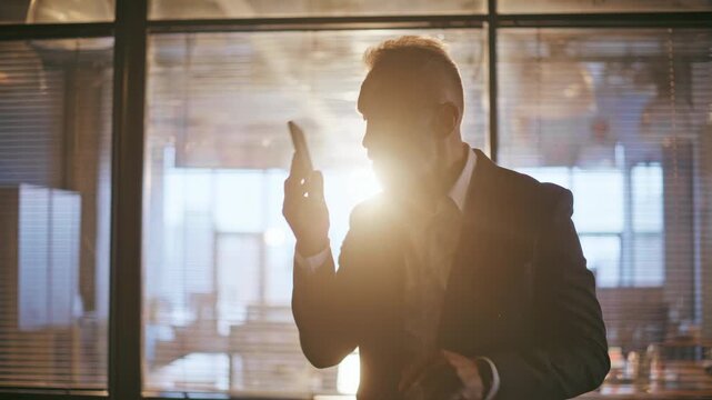 Silhouette boss yelling mobile phone standing office corridor in sunset light closeup. 