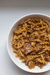 Delicious creamy pasta with chanterelle mushrooms served in a white bowl. Top down food shot for recipe blogs, cooking magazines, or restaurant menus. Rustic comfort food at its best.