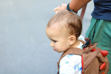 Toddler with playful backpack holding adult's hand