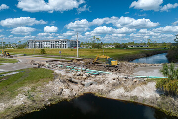 Destroyed bridge after hurricane flooding in Florida. Construction equipment at roadwork site....
