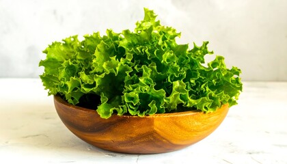 Fresh, vibrant green lettuce leaves fill a wooden bowl on a light background.
