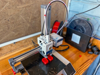 3d printer creating red plastic parts in workshop