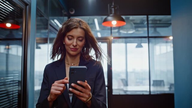 Smiling lady reading cellphone message walking hallway in elegant suit closeup.