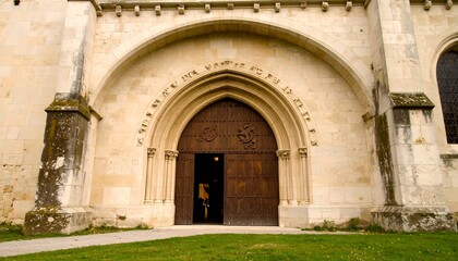 Obraz premium Grand Arched Entrance of a Historic Stone Church with Large Wooden Doors.