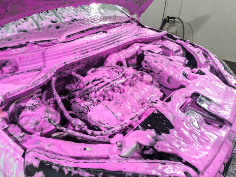 Cleaning the car engine with a special chemically active foam. Washing the engine at a car wash.
