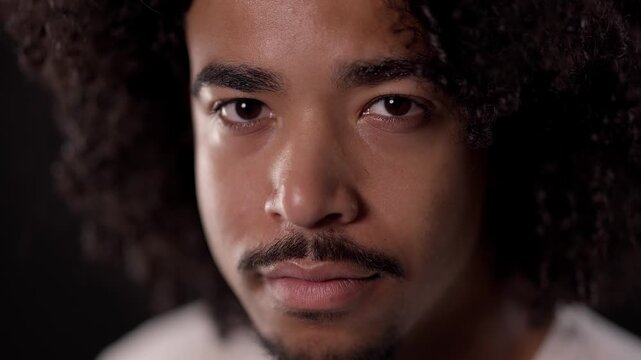 Close up portrait of a serious young African-American man with curly hair and goatee
