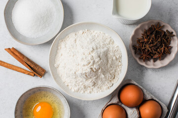 Baking ingredients flat lay with flour, eggs, sugar, and spices on marble surface