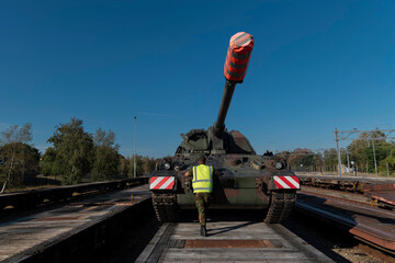Front view of PZH2000NL artillery system with military personnel on railroad transport platform