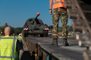 Military personnel coordinating artillery transport operations with safety equipment and...