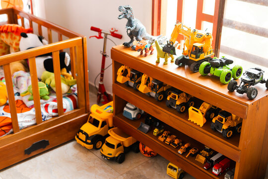 Habitaci&oacute;n infantil con cuna de madera y estanter&iacute;a organizada con juguetes, carros y dinosaurios, creando un espacio colorido para el juego y la infancia.
