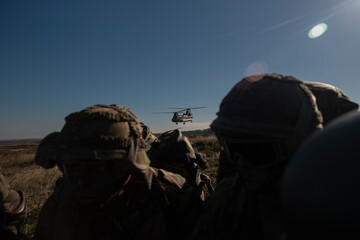 Soldiers observing military helicopter operations during tactical field exercise