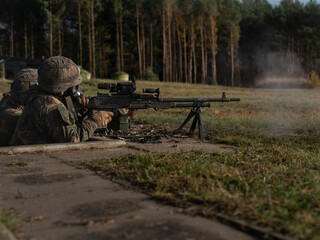 Military weapons team in defensive position with machine gun in wooded training area