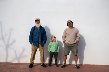 Three generations of family, grandfather with white beard, father in casual clothes, and little son...