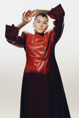 young woman posing confidently in a long red leather coat with stylish short hair, clean white...