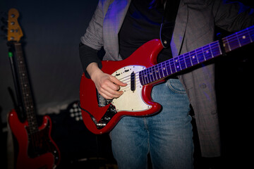 Obraz premium Musician playing red electric guitar in concert setting with blue lighting
