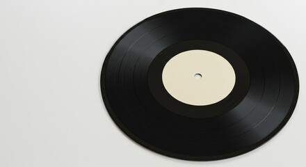A black vinyl record with a blank white label centered on a white surface in a high angle shot view