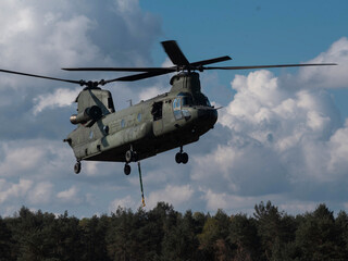 Dramatic low angle view of Chinook helicopter underside against blue sky with white clouds © Victor