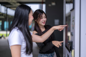 Two young women using modern touch screen vending machine