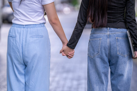 Two students walking and holding hands outdoors