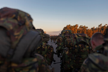Soldiers in formation walking during evening light with dramatic sky background