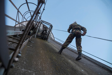 Soldier rappelling down rope during tactical training exercise from elevated structure