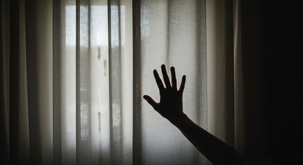 Silhouette of a hand against sheer curtains with daylight
