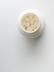 Close up of light Round Pills in White Plastic Bottle