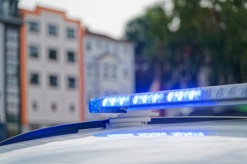 Blue flashing police lights on roof of car with houses behind