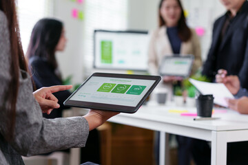 Digital tablet with business dashboard held by person in modern office meeting, colleagues...