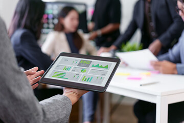 Business team meeting in modern office with tablet displaying ESG data, diverse professionals...