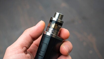 Close-up of a hand-held electronic vaping device with a dark gray background.