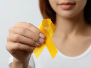 Woman showing yellow ribbon, representing bone cancer, suicide prevention and endometriosis awareness