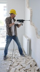 Male construction worker demolishing concrete wall with rotary hammer, wearing safety gear and...
