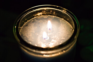 Close-up of a double-wick candle glowing warmly in soft focus, creating a soothing atmosphere perfect for relaxation, mindfulness, or romantic settings.