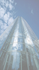 Modern Glass Skyscraper Reflecting Clouds Against a Blue Sky, Low Angle View
