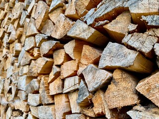 Pile of stacked chopped firewood pieces ready for storage and use in fireplace or stove