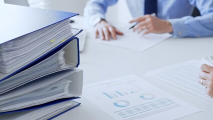 Group of accountants are analyzing financial reports and making notes while sitting at a white...