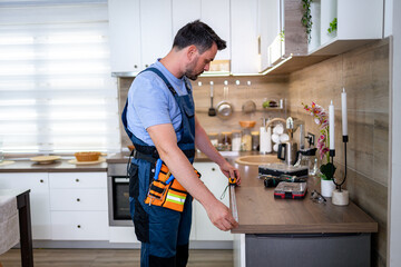 Worker measures countertop space in modern kitchen during home renovation project